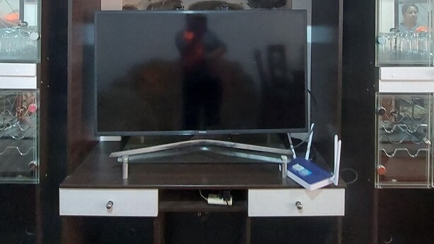 Un meuble pour télévision avec un téléviseur à écran plat, une étagère avec des objets décoratifs et un mur en pierre.