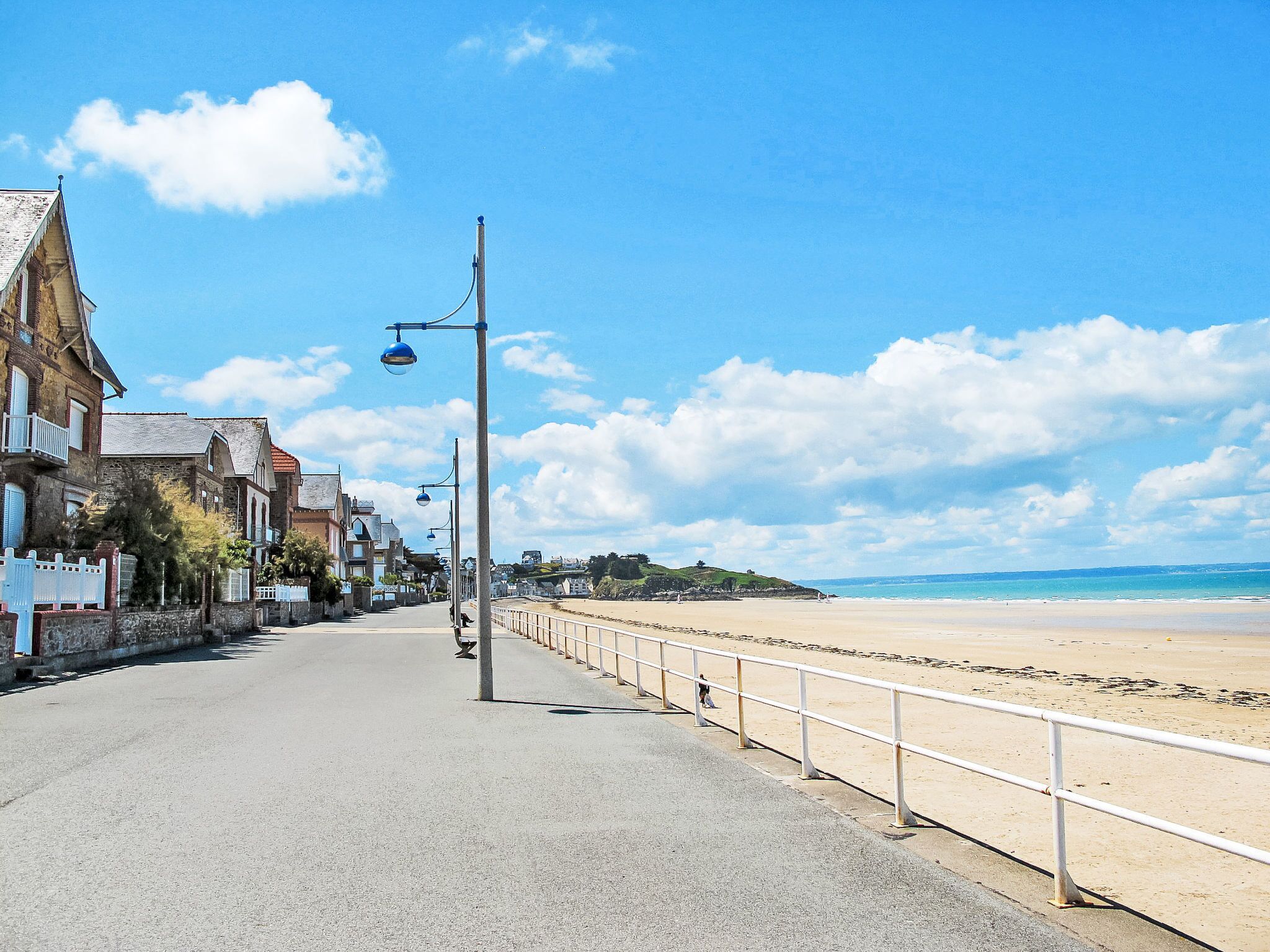 Een kuststraat met gebouwen, een strand en een heldere lucht.