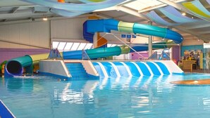 Ein Hallenbad mit mehreren Wasserrutschen und einer klaren Wasseroberfläche.