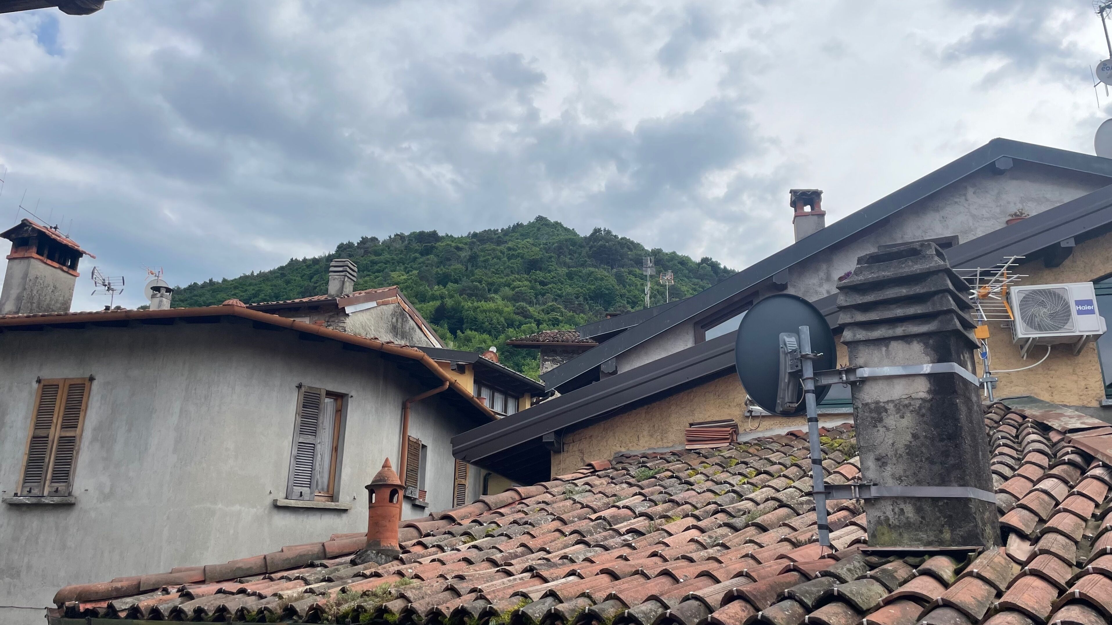A traditional building with a tiled roof, a satellite dish, and a chimney.