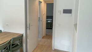 Käytävällä on puulattia, ja se johtaa huoneeseen, jossa on sänky ja yöpöytä.