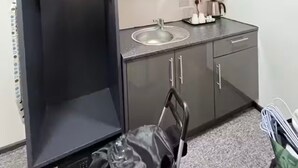 Une cuisine compacte équipée d’un four à micro-ondes encastré, d’un évier et d’un petit plan de travail.