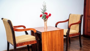 A wooden table with two chairs, a vase with red flowers, and a wooden floor. - The Golden Legacy Hotel (Nuwara Eliya)