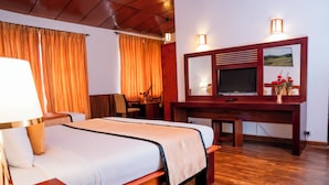 A hotel room with a bed, desk, TV, and wooden flooring. - The Golden Legacy Hotel (Nuwara Eliya)