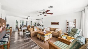 A spacious living room with a sofa, coffee table, wicker chairs, and a dining area with a table and chairs. - Palm Paradise (Cocoa Beach)