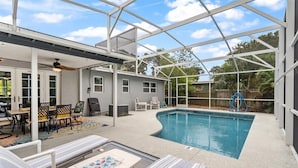 A covered outdoor swimming pool area with lounge chairs and a patio table. - Palm Paradise (Cocoa Beach)