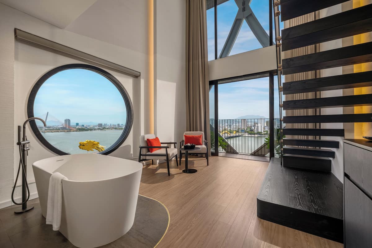 Une salle de bain moderne avec une baignoire, une fenêtre ronde et une vue sur le paysage urbain.