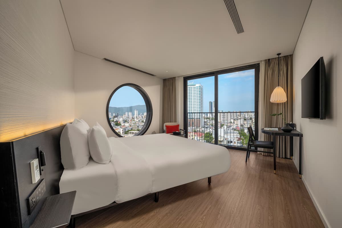 Une chambre d’hôtel moderne dotée d’un grand lit, d’un bureau, d’une chaise, d’une télévision et offrant une vue sur la ville.