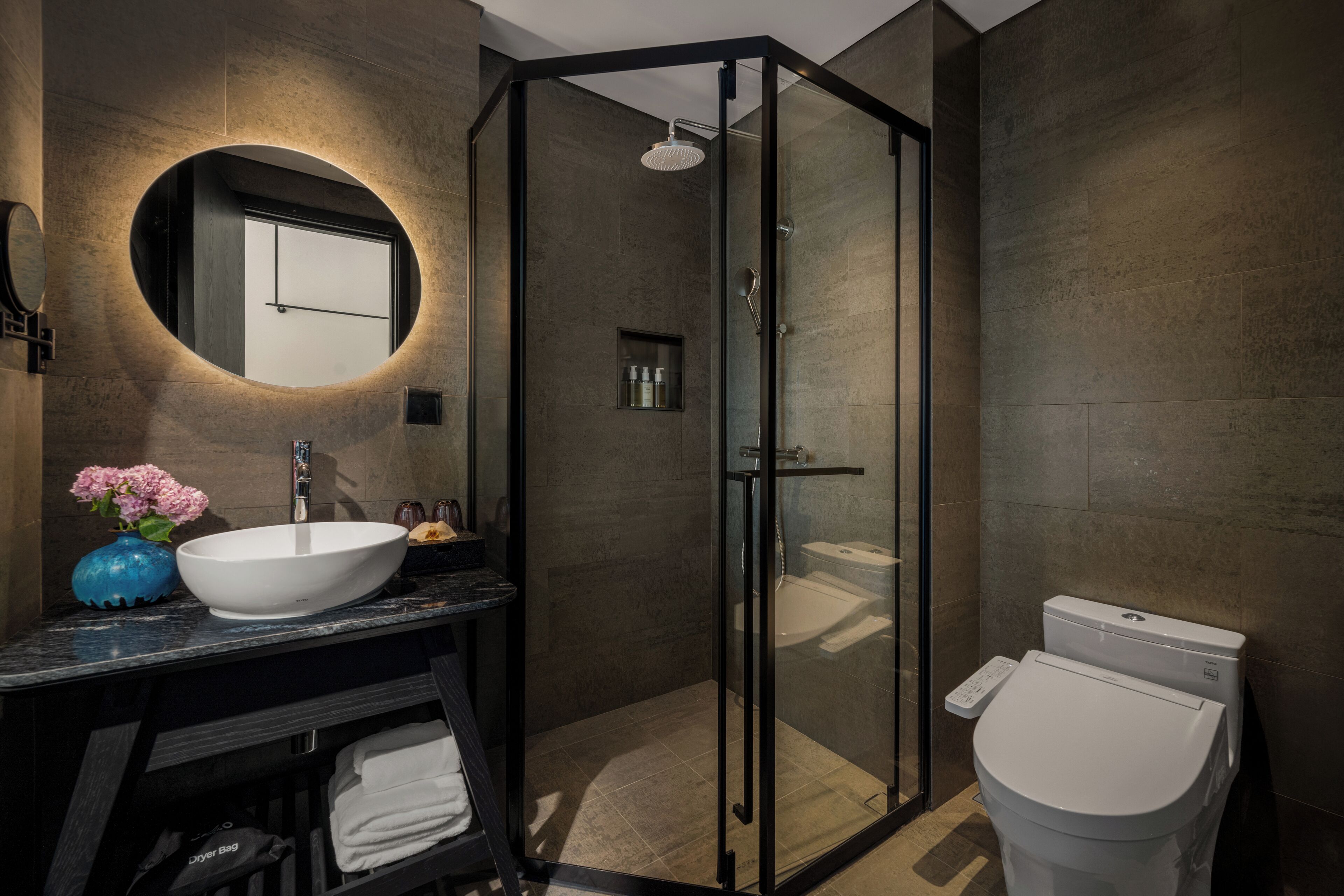 A modern bathroom with a glass-enclosed shower, a large white sink, and a toilet.