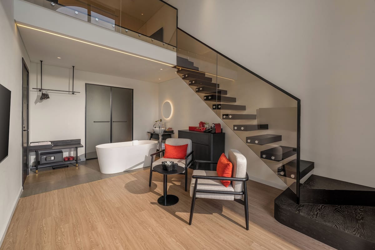 Un salon moderne avec un escalier, une grande fenêtre et un design minimaliste.