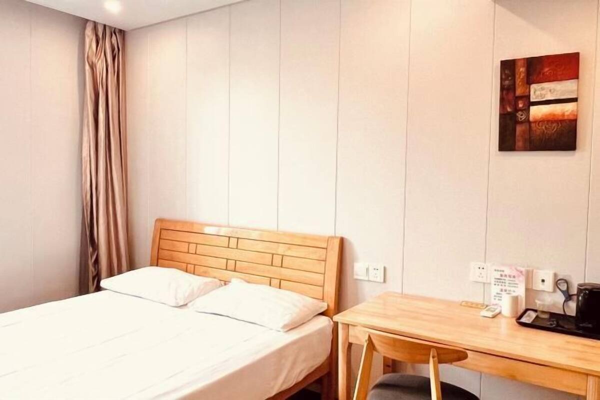 A hotel room with a wooden bed, a desk, and a wall-mounted artwork.