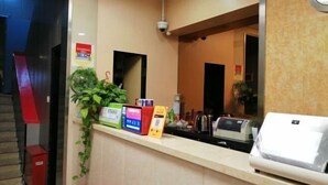 Un espace d’accueil comprenant un comptoir, une caméra de surveillance, une plante et un kiosque numérique.