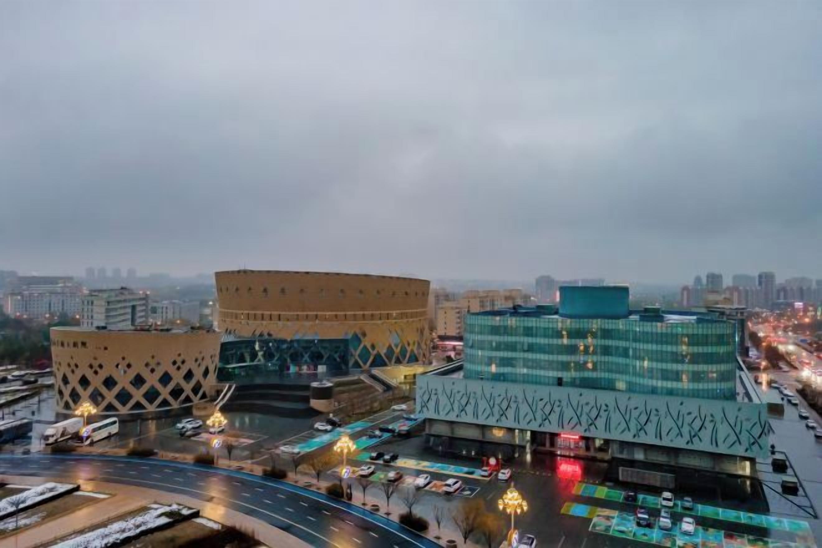 A cityscape with modern buildings, a roundabout, and a busy road with vehicles.