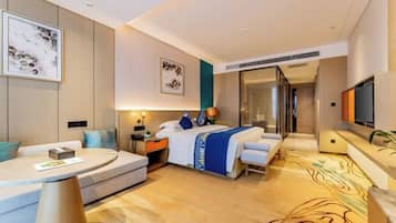 A hotel room with a bed, a sofa, a desk, a TV, and a bathroom.
