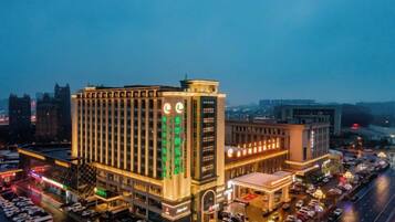 A large hotel with multiple floors, a prominent clock tower, and a parking lot with numerous cars.