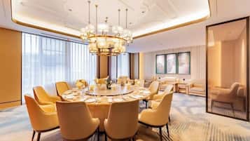 A modern dining room with a round table, multiple chairs, and a chandelier.