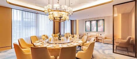 A modern dining room with a round table, multiple chairs, and a chandelier.