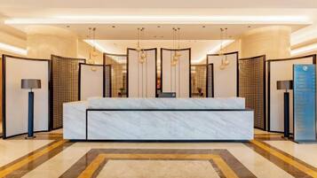 A hotel lobby with a reception desk, a large seating area, and a patterned floor.