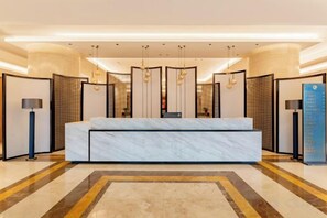 A hotel lobby with a reception desk, a large seating area, and a patterned floor. - Ordos Taihua Langjing Hotel (Ordos)