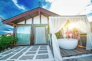 Relax in a serene outdoor space with a bathtub and covered seating area.