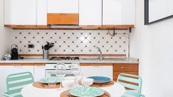 Una cocina compacta con armarios blancos, un backsplash de azulejos y una mesa redonda con sillas.