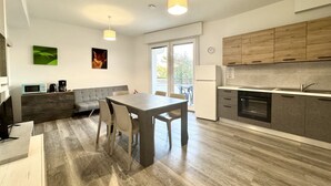 A modern kitchen with a dining area, wooden cabinets, and a large window.
