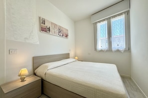 Una camera da letto con un letto, un comodino, una lampada e una finestra con tende.