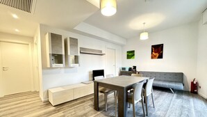 A modern living room with a dining table, grey sofa, and a built-in bench.