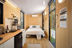 A compact hotel room with a bed, kitchenette, and a view of the outdoors. - JJJ's Ranch Farm 1 by Tiny Away (South Kolan)
