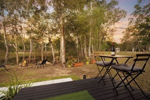 An outdoor seating area with a table and chairs, a fire pit, and potted plants. - JJJ's Ranch Farm 1 by Tiny Away (South Kolan)
