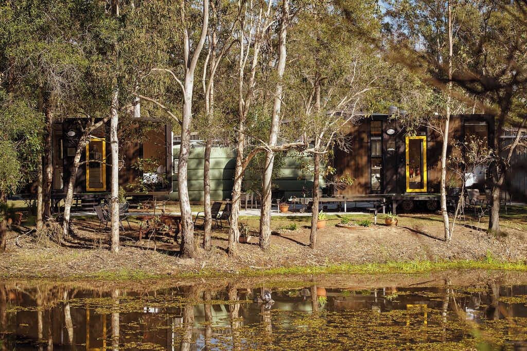 Un chalet au bord du lac, doté d’un quai, entouré d’arbres et bordé d’un petit étang.