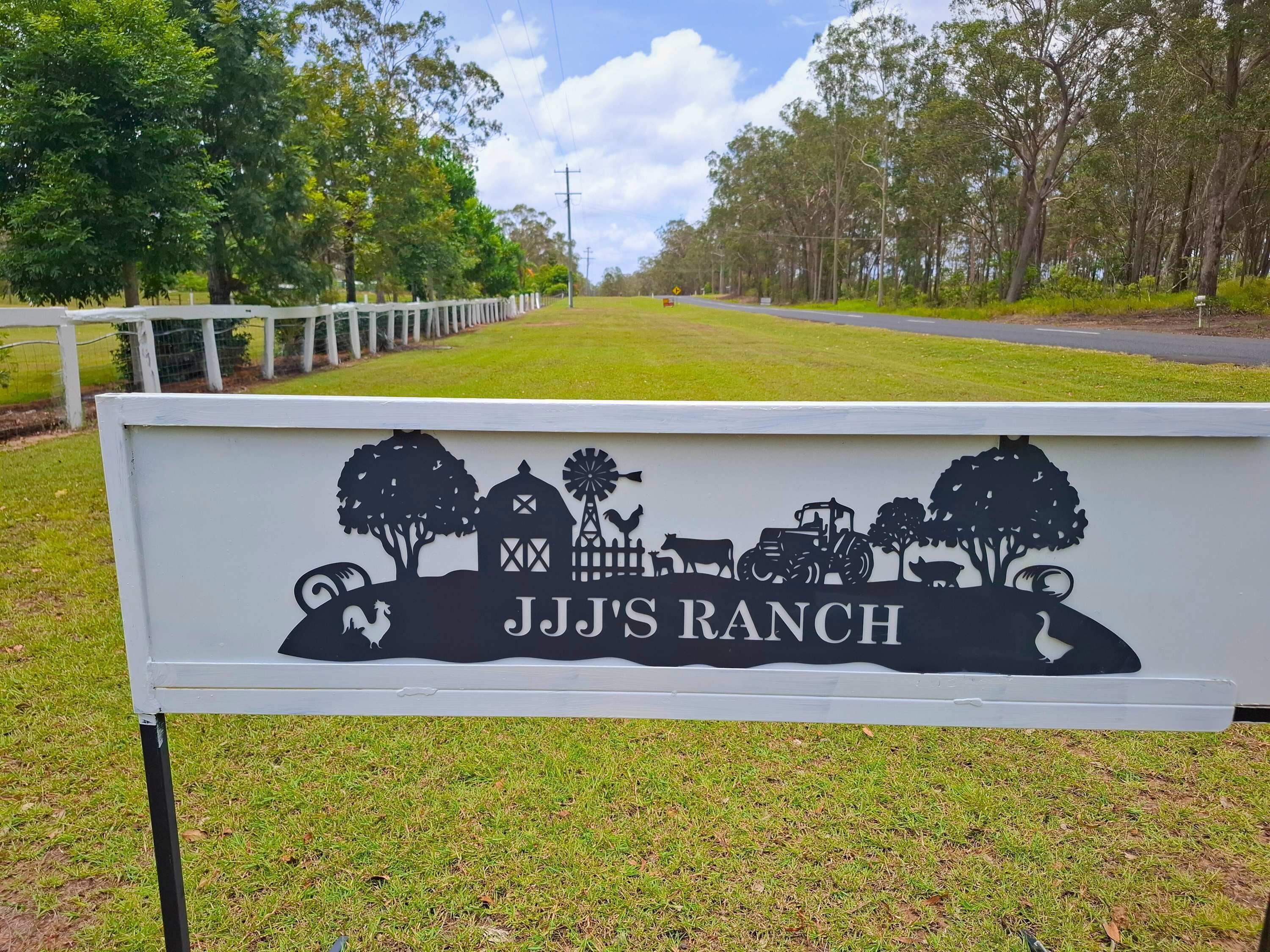 A sign for JJJ Ranch with a silhouette of farm elements.