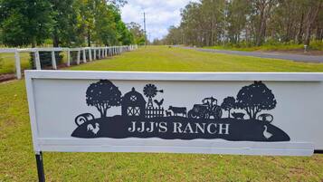 A sign for JJJ Ranch with a silhouette of farm elements.