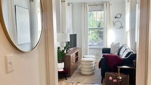 A room with a wooden floor, a sofa, a table, and a mirror.