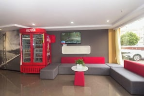 A modern lobby with a red telephone booth, a flat-screen TV, and a seating area with grey and red sofas. - Shankee Hotel (Shanghai Baoshan Yanghang Town) (Shanghai)