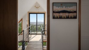 A staircase leading to a balcony with a mountain view, a deer head decoration, and a landscape painting. - Mountain cabin w/ hot tub & game room (Romney)