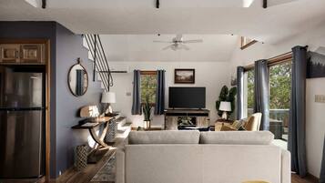 A modern living room with a sofa, TV, and dining area.