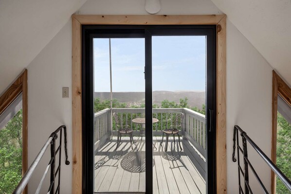 A balcony with a wooden deck, metal railing, and two round tables.