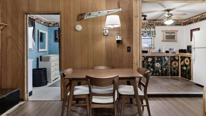 A dining area with a wooden table and chairs, a ceiling fan, and a kitchen in the background. - Wood Stove, Fire Pit, Kayaks - 2 Min Walk to River (Springfield)