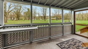 A covered porch with a view of a grassy field and trees. - Wood Stove, Fire Pit, Kayaks - 2 Min Walk to River (Springfield)