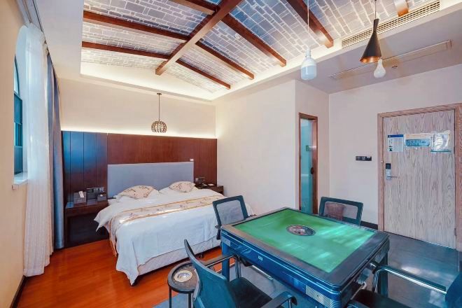 A hotel room with a bed, a pool table, and a wooden ceiling.