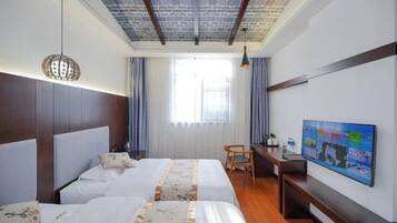 A hotel room with two beds, a desk, a television, and a window with curtains.