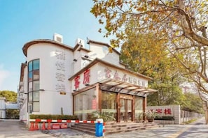 A hotel with a traditional architectural style, featuring a curved facade and a prominent entrance with glass doors. - Fuchun Ju Yayue Hotel (Wusongkou International Cruise Port) (Shanghai)