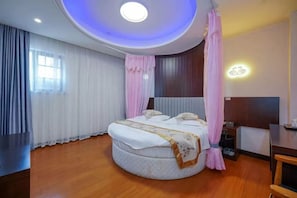 Une chambre d’hôtel avec un lit rond, un plafond également rond, une table de chevet et une petite table de nuit.