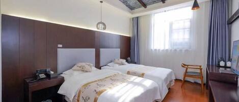 A hotel room with two beds, a desk, and a chair.