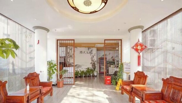 Un interior de estilo tradicional con muebles de madera, un pasillo central y detalles decorativos como plantas y un adorno rojo.