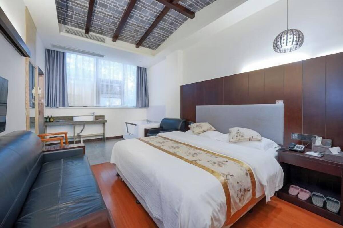 Ett hotellrum med en stor säng, ett skrivbord, en soffa och utsikt över staden.