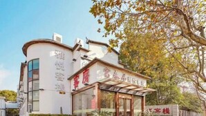 Un hotel con un estilo arquitectónico tradicional, que presenta una fachada curva y una entrada destacada con puertas de vidrio.