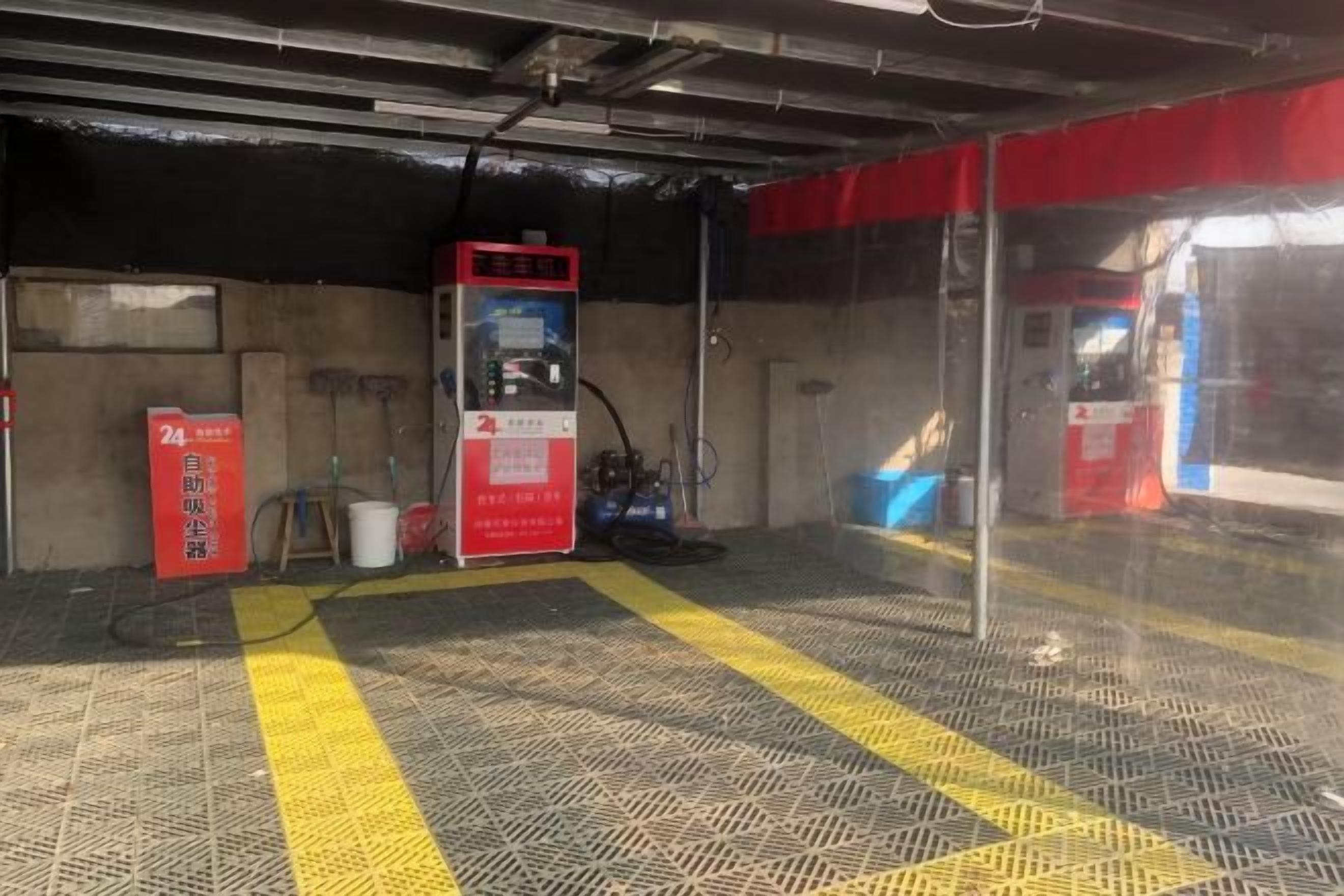 A gas station with a red fuel pump, a yellow safety line on the floor, and a red sign with white text.