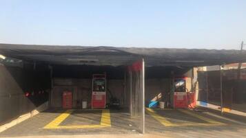 A covered parking area with a fuel pump, a fire extinguisher, and a red emergency phone.